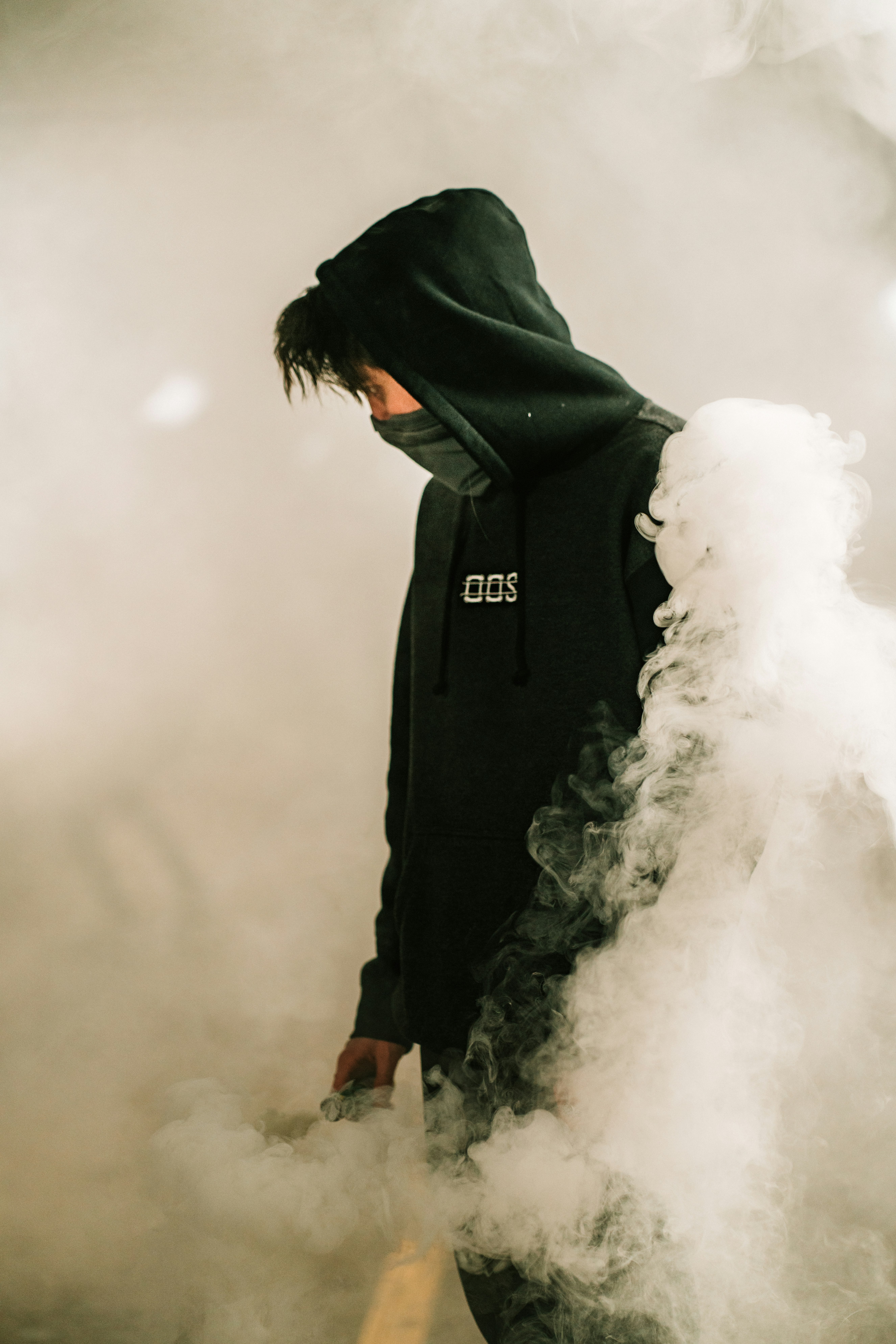 person in black hoodie standing on white smoke